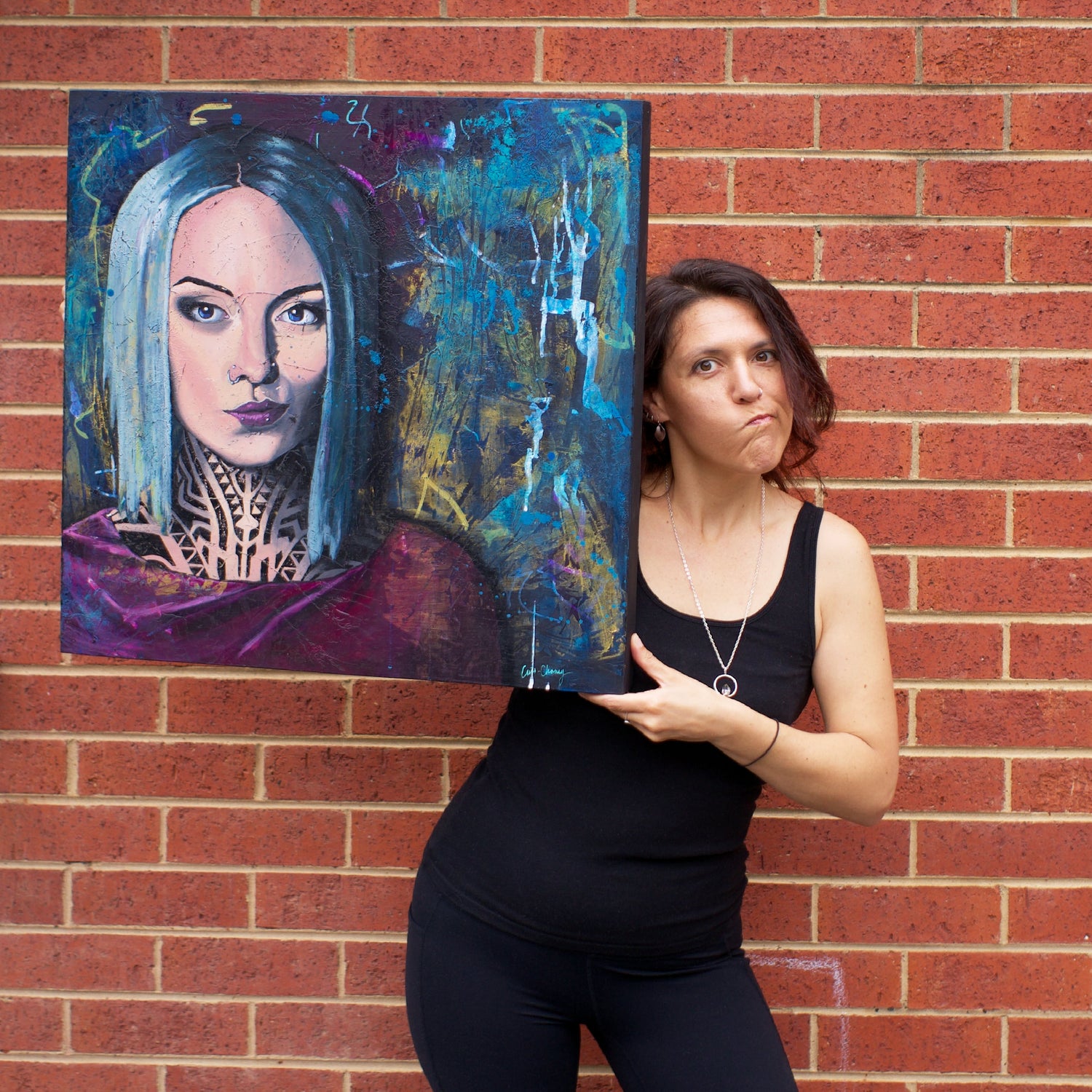 artist criss chaney with her painting of teya salat portrait of a woman with a neck tattoo