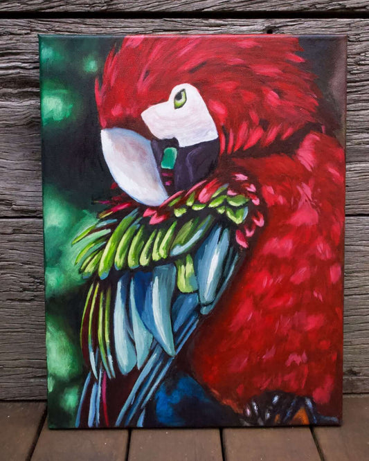 Milan Art Institute Mastery Program Review Criss Chaney An oil painting of a colorful parrot with red, blue, and green feathers, displayed on a wooden surface.