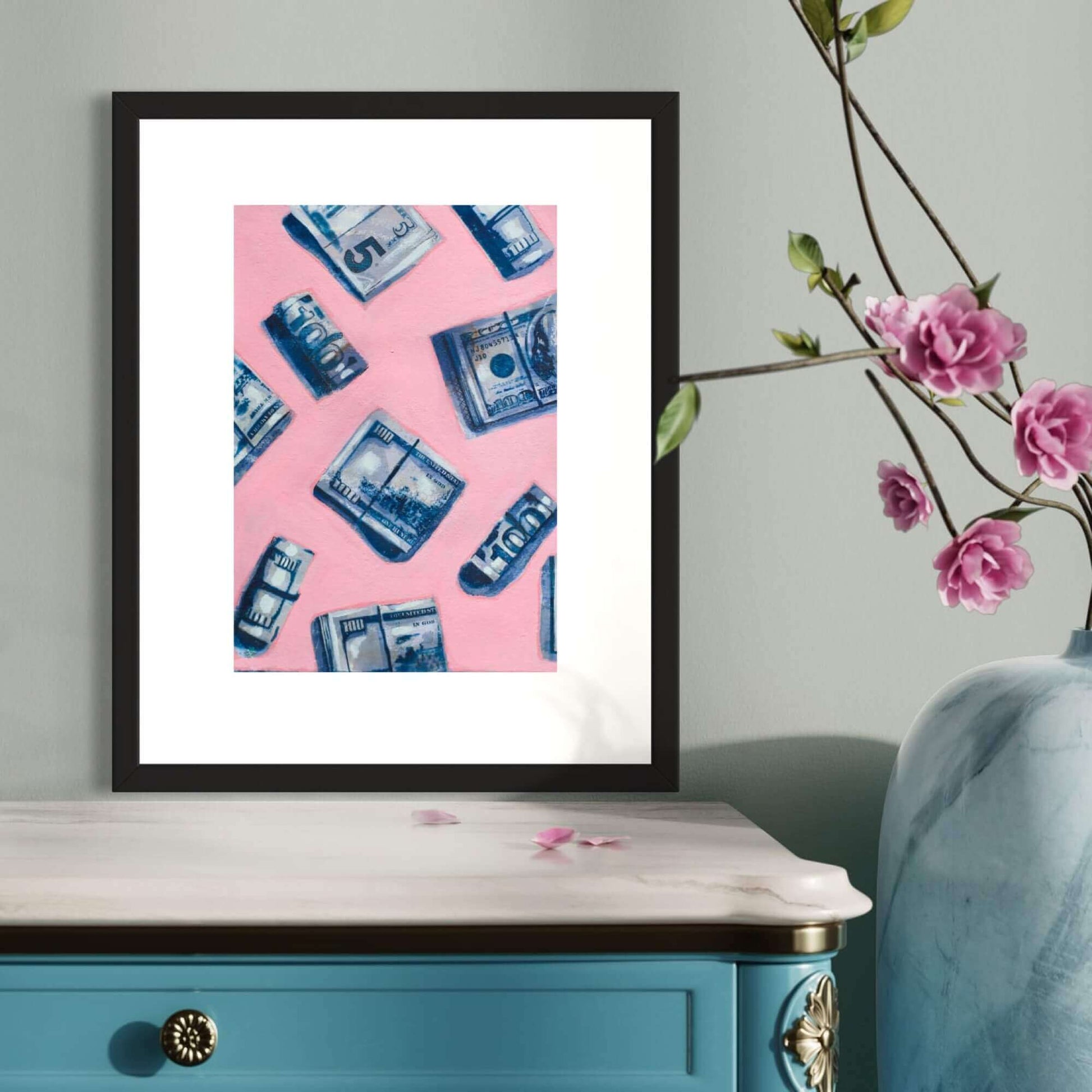 A framed artwork featuring a repeating pattern of blue and white dollar bills on a pink background