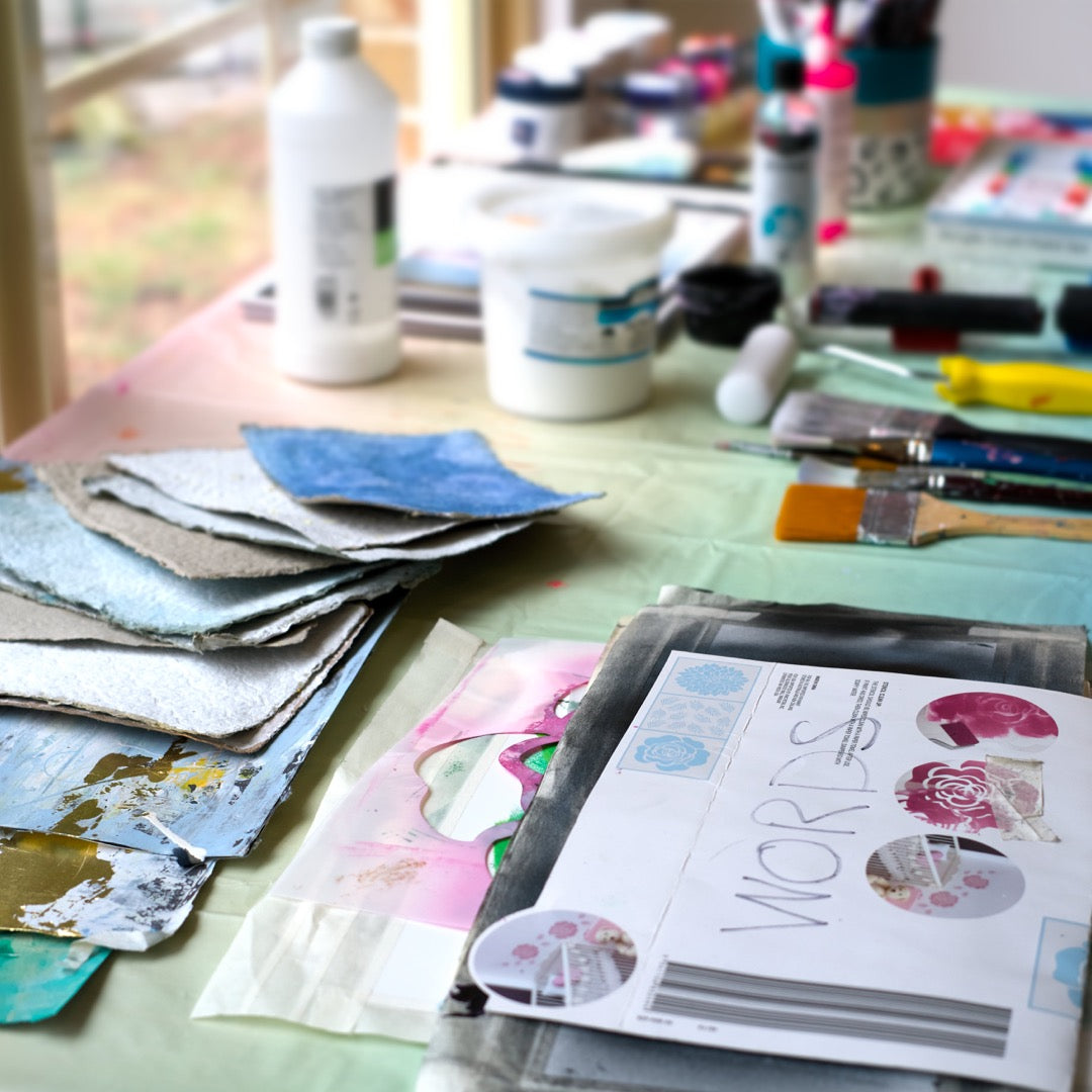 Art Classes in Berwick, Painting classes Criss Chaney. Artistic workspace with paint samples, brushes, and a notebook on a table.