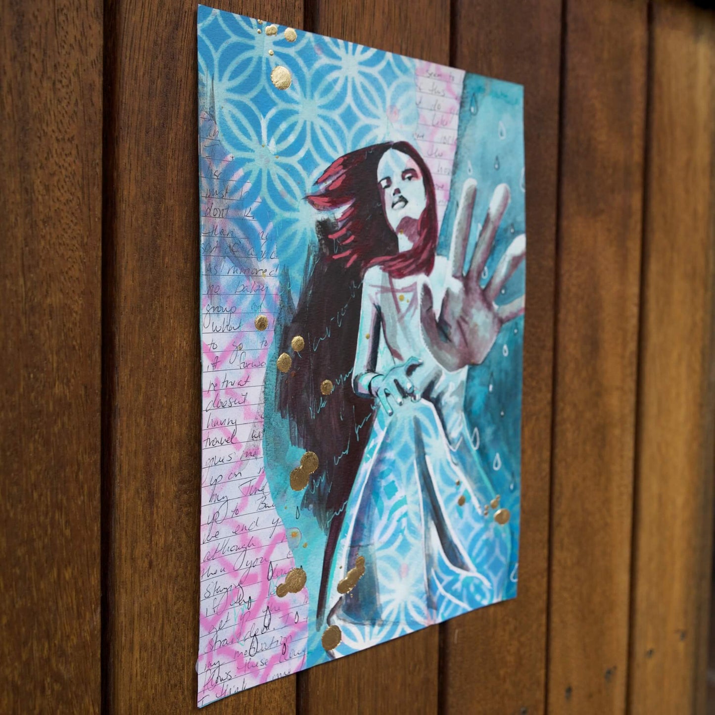 blue painting of a woman reaching out to viewer with gold leaf splatters